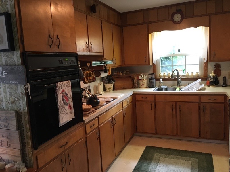 This is an example of a small traditional u-shaped eat-in kitchen in Other with an undermount sink, raised-panel cabinets, brown cabinets, quartzite benchtops, yellow splashback, porcelain splashback, stainless steel appliances, vinyl floors, no island and beige floor.