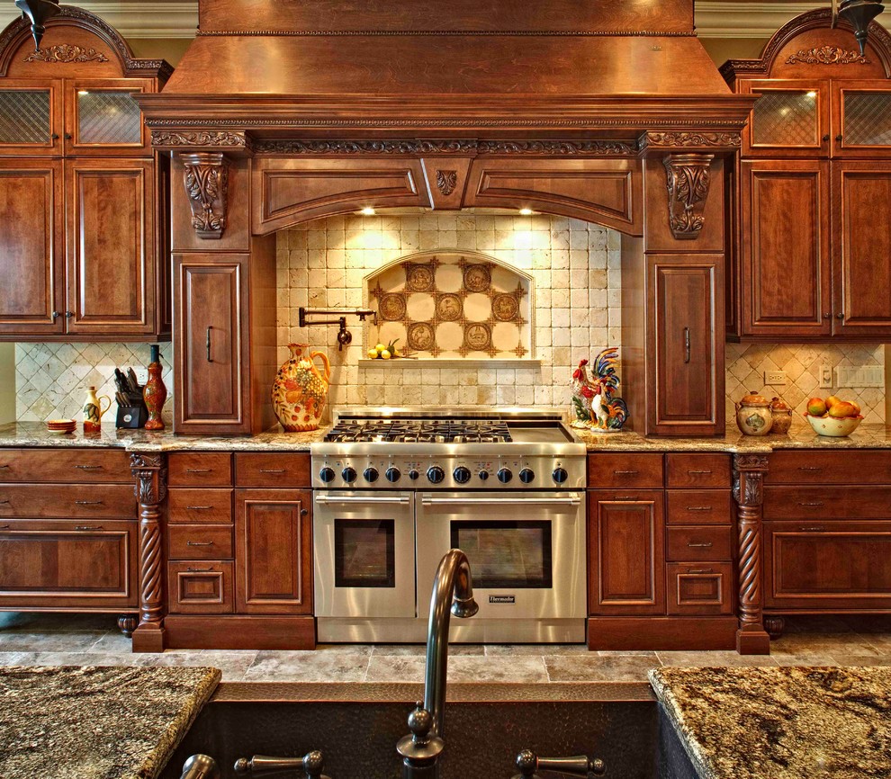 This is an example of a large traditional kitchen in Chicago with raised-panel cabinets, dark wood cabinets, granite benchtops, beige splashback, stone tile splashback, stainless steel appliances, an undermount sink, porcelain floors, with island and grey floor.