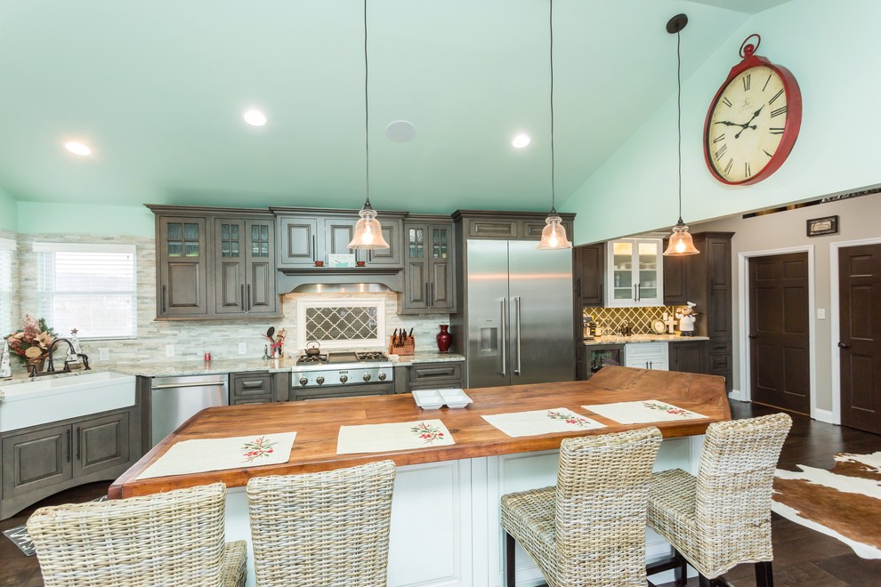 Inspiration for a country eat-in kitchen in St Louis with a farmhouse sink, raised-panel cabinets, brown cabinets, wood benchtops, beige splashback, matchstick tile splashback, stainless steel appliances, medium hardwood floors and with island.