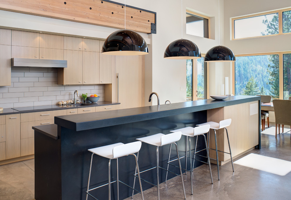 Inspiration for a mid-sized contemporary eat-in kitchen in Other with flat-panel cabinets, light wood cabinets, concrete benchtops, ceramic splashback, concrete floors, with island, beige floor, beige splashback and panelled appliances.