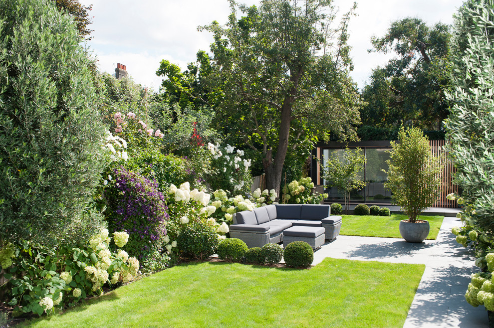 Geometrischer, Großer Moderner Garten im Sommer, hinter dem Haus mit Blumenbeet, direkter Sonneneinstrahlung, Natursteinplatten und Holzzaun in London