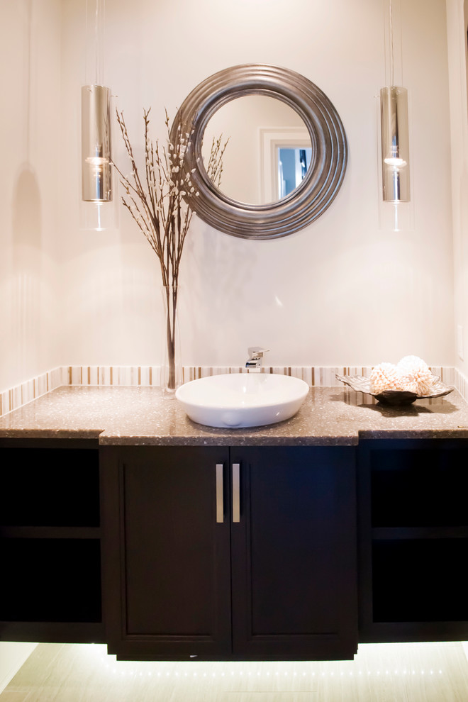 This is an example of a mid-sized transitional powder room in Vancouver with recessed-panel cabinets, dark wood cabinets, beige walls, porcelain floors, a vessel sink and beige floor.