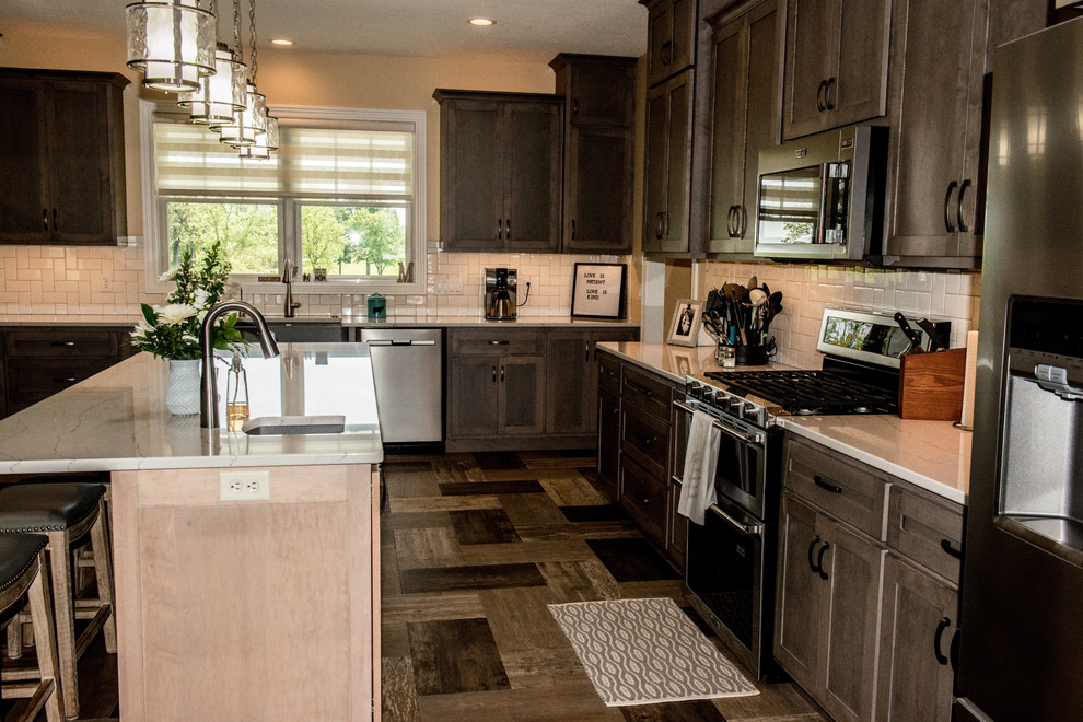 Open concept kitchen - large transitional l-shaped vinyl floor and multicolored floor open concept kitchen idea with a farmhouse sink, shaker cabinets, gray cabinets, quartz countertops, white backsplash, subway tile backsplash, stainless steel appliances, an island and white countertops