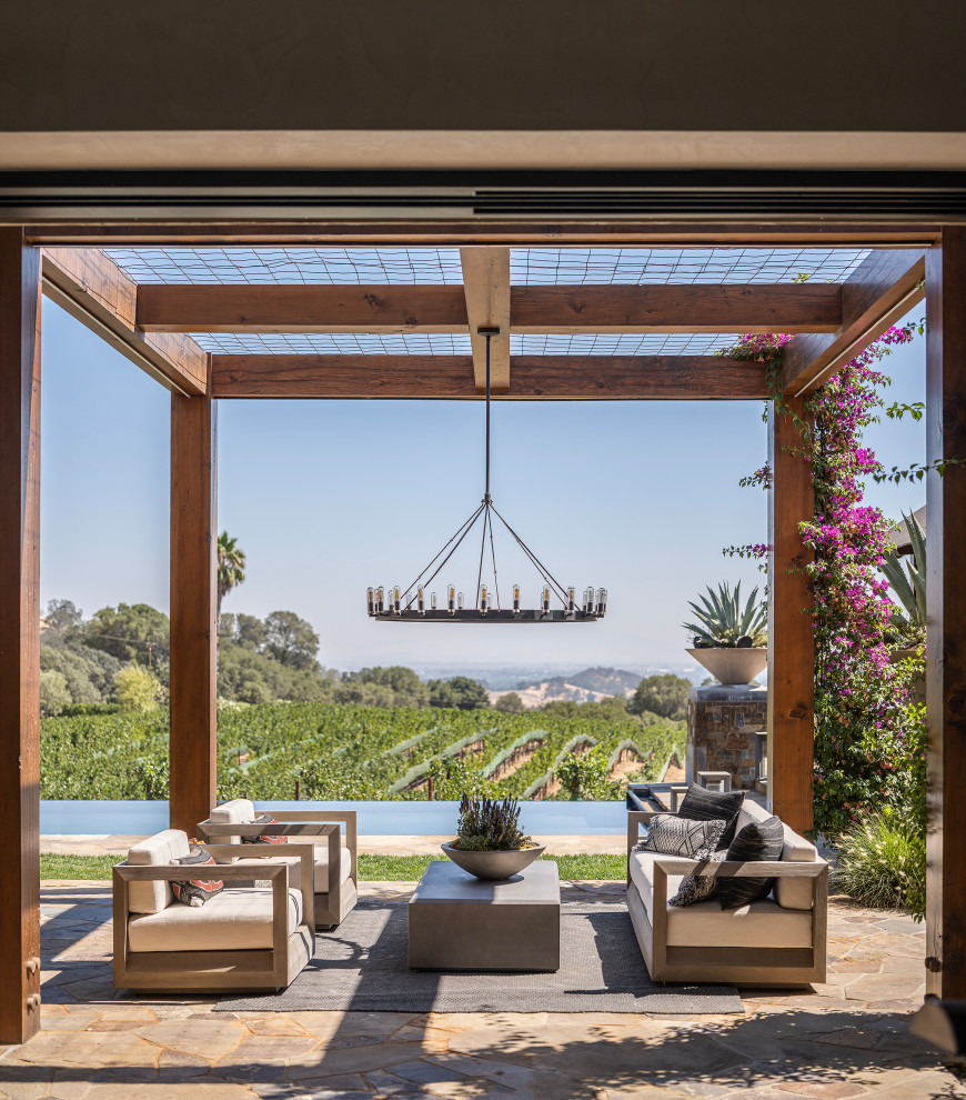 Photo of an expansive farmhouse side patio in San Francisco with natural stone paving and a pergola.