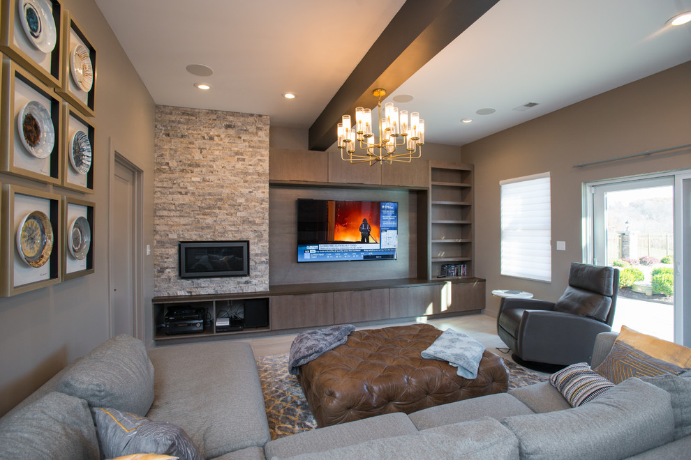 This is an example of a large modern walk-out basement in Other with beige walls, a ribbon fireplace, a stone fireplace surround and grey floor.