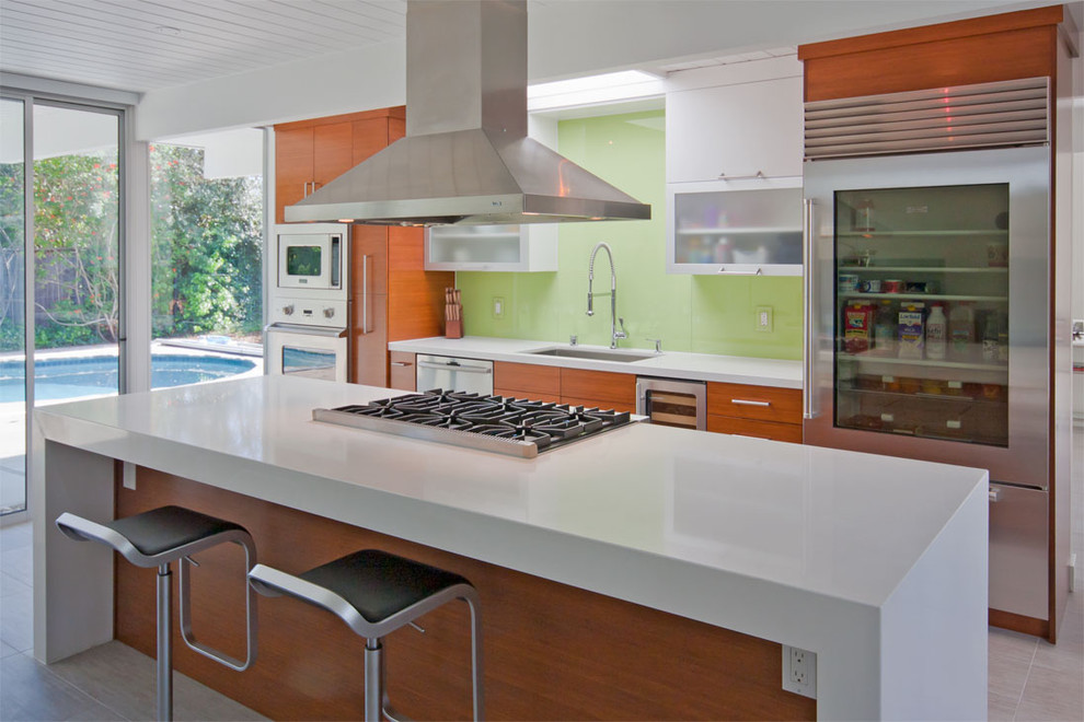 Inspiration for a mid-sized contemporary galley eat-in kitchen in San Francisco with stainless steel appliances, flat-panel cabinets, quartz benchtops, green splashback, glass sheet splashback, porcelain floors, medium wood cabinets and with island.