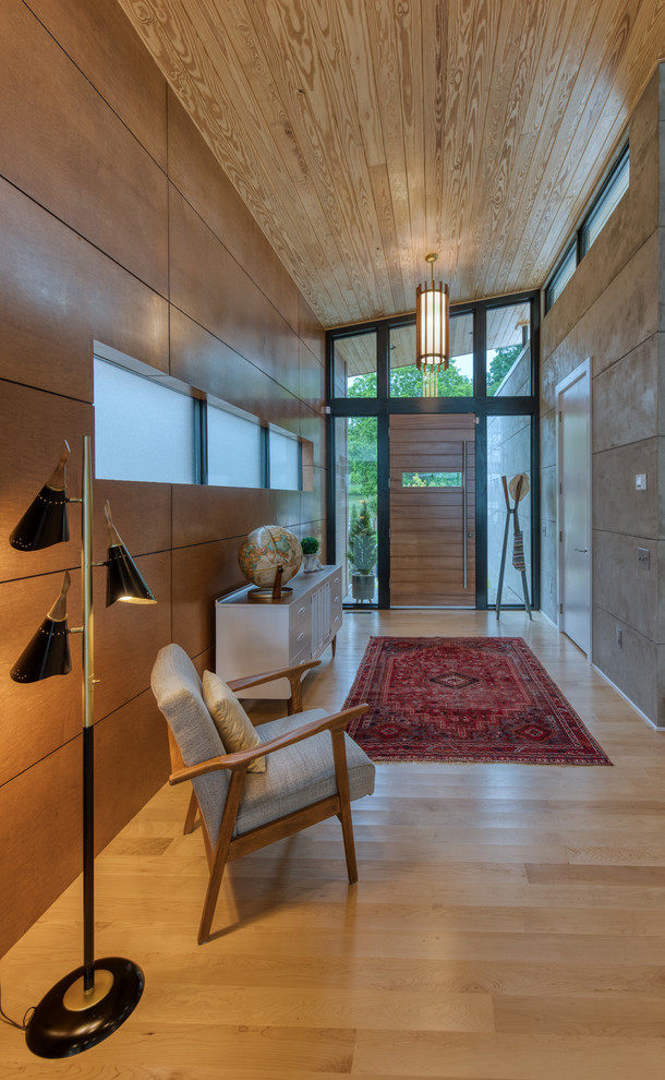 This is an example of a mid-sized midcentury front door in Other with brown walls, light hardwood floors, a medium wood front door and white floor.