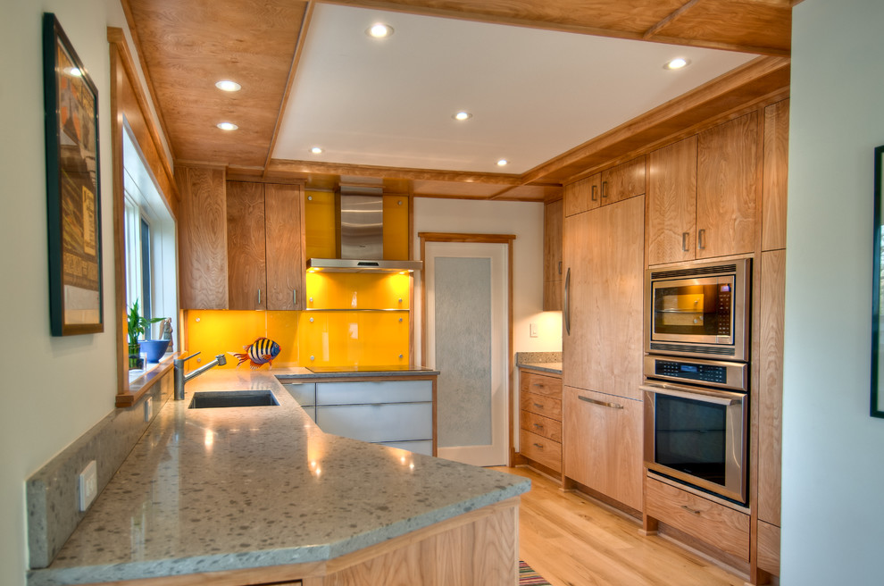 Transitional u-shaped enclosed kitchen photo in DC Metro with an undermount sink, flat-panel cabinets, light wood cabinets, solid surface countertops, orange backsplash, glass sheet backsplash and stainless steel appliances