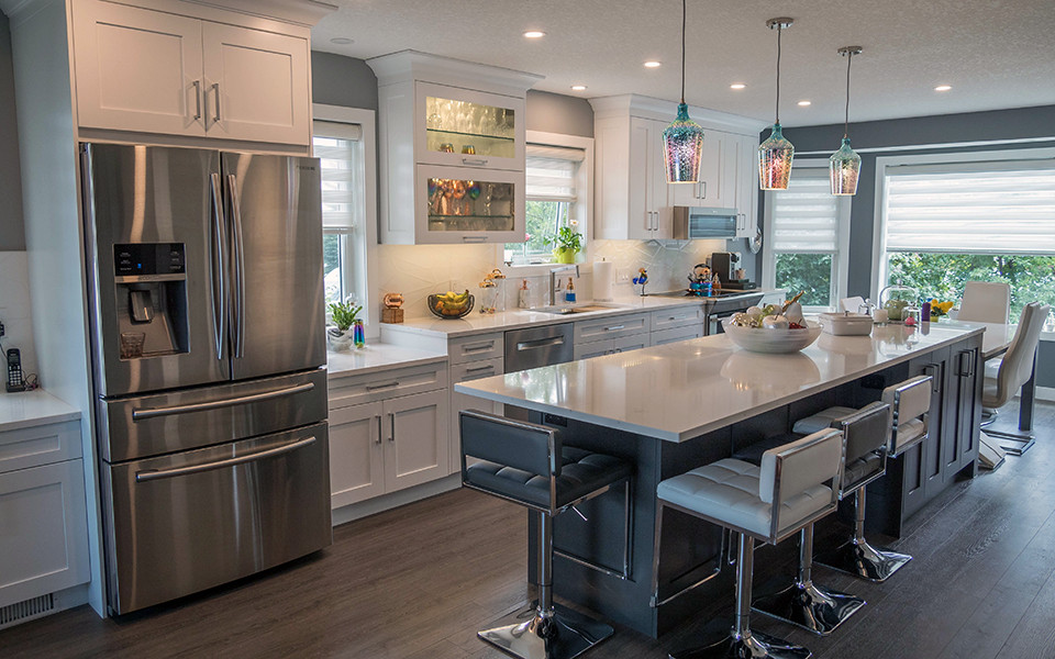Example of a mid-sized transitional galley vinyl floor and brown floor kitchen design in Calgary with an undermount sink, shaker cabinets, white cabinets, quartz countertops, white backsplash, porcelain backsplash, stainless steel appliances, an island and white countertops