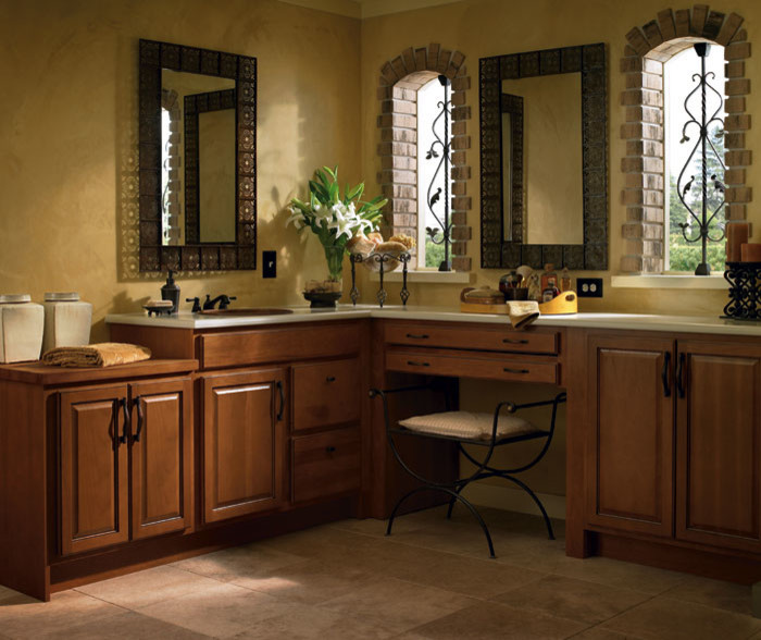 This is an example of a mid-sized mediterranean master bathroom in Other with raised-panel cabinets, medium wood cabinets, yellow walls, porcelain floors, an undermount sink and brown floor.