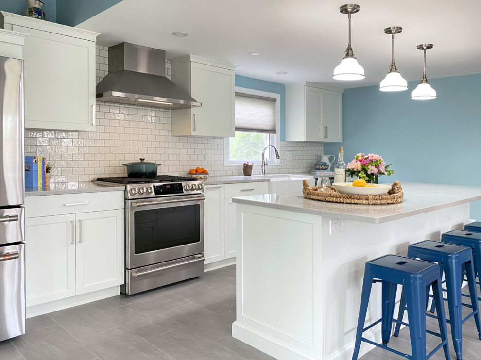 Design ideas for a transitional eat-in kitchen in Boston with a farmhouse sink, raised-panel cabinets, white cabinets, quartz benchtops, white splashback, ceramic splashback, stainless steel appliances, porcelain floors, with island, grey floor and white benchtop.