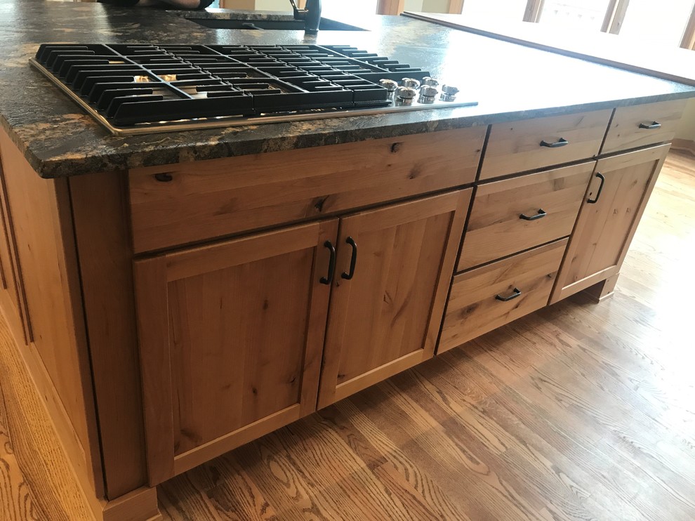 Large mountain style l-shaped medium tone wood floor and brown floor home design photo in Chicago with an undermount sink, shaker cabinets, medium tone wood cabinets, granite countertops, green backsplash, slate backsplash, stainless steel appliances, an island and black countertops