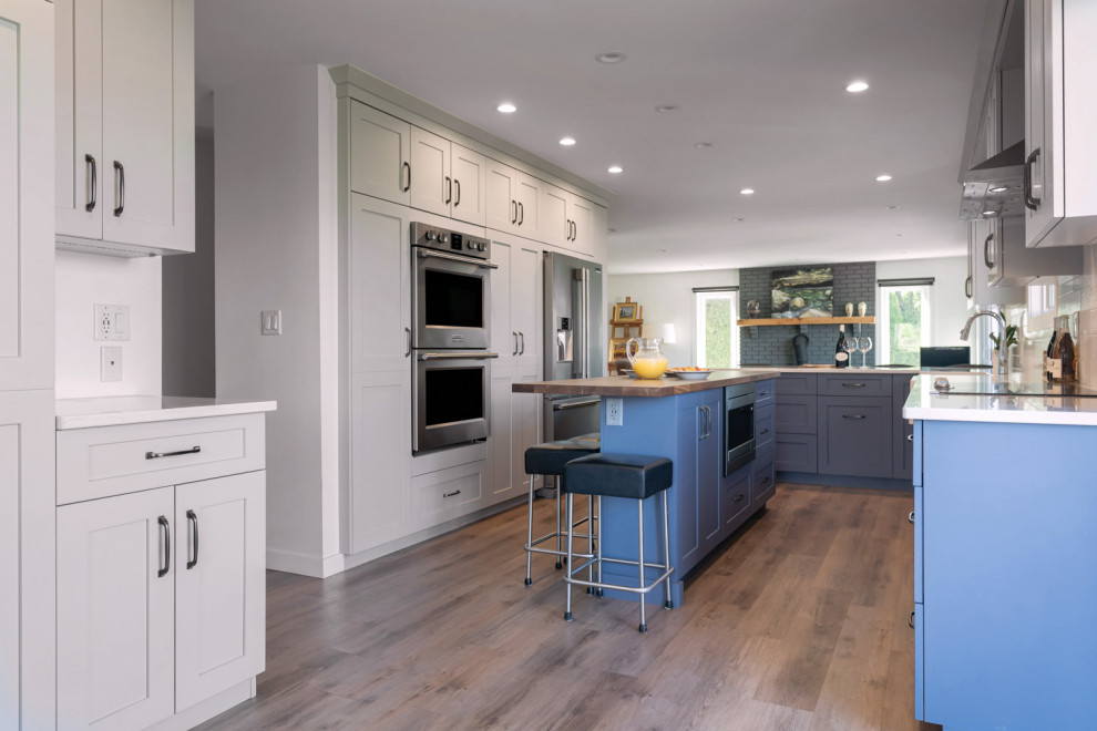Inspiration for a mid-sized transitional u-shaped medium tone wood floor and brown floor eat-in kitchen remodel with recessed-panel cabinets, gray cabinets, quartz countertops, white backsplash, ceramic backsplash, stainless steel appliances, an island and white countertops