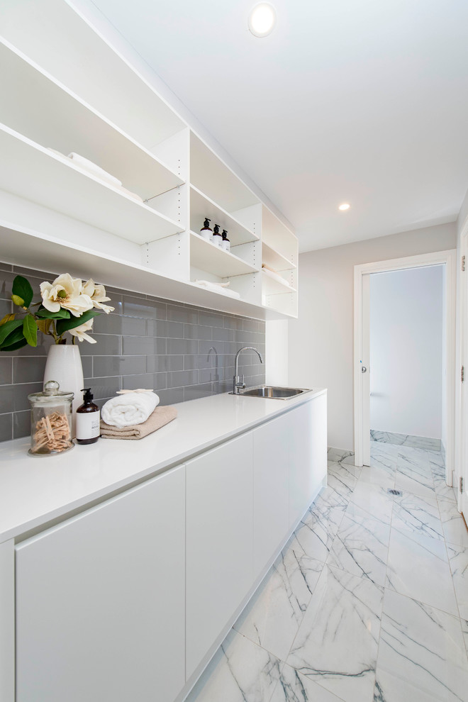 Photo of a mid-sized contemporary galley dedicated laundry room in Canberra - Queanbeyan with a drop-in sink, white walls and ceramic floors.