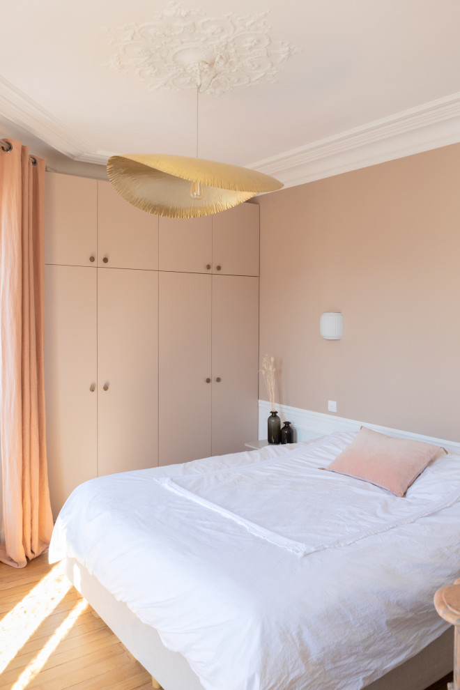 Foto de dormitorio principal minimalista de tamaño medio con paredes rosas, suelo de madera en tonos medios, todas las chimeneas, marco de chimenea de piedra y suelo marrón