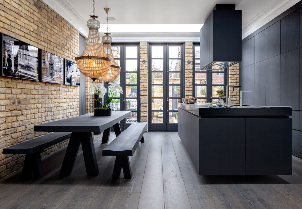 Photo of a mid-sized industrial galley eat-in kitchen in London with flat-panel cabinets, black cabinets, concrete benchtops, panelled appliances, dark hardwood floors, with island and brown floor.