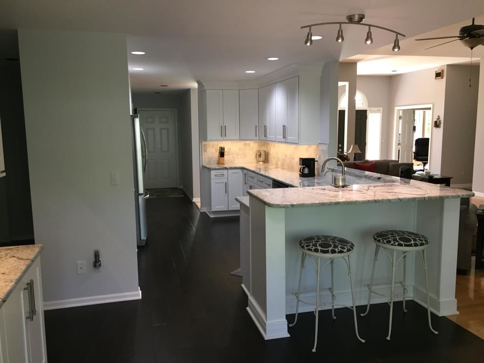 Example of a mid-sized transitional u-shaped dark wood floor eat-in kitchen design in Detroit with an undermount sink, shaker cabinets, white cabinets, granite countertops, white backsplash, stone tile backsplash, stainless steel appliances and a peninsula