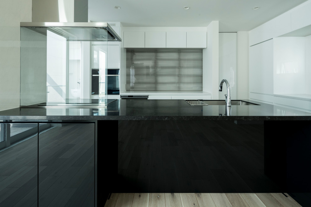 Inspiration for a large modern single-wall open plan kitchen in Other with an undermount sink, flat-panel cabinets, black cabinets, quartz benchtops, white splashback, black appliances, porcelain floors, a peninsula, grey floor, black benchtop and timber.
