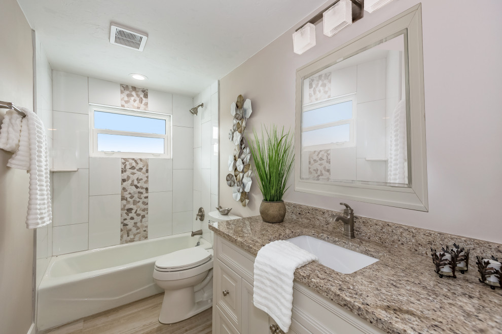 Inspiration for a large modern bathroom in Tampa with raised-panel cabinets, white cabinets, a shower/bathtub combo, white tile, marble, grey walls, porcelain floors, an undermount sink, granite benchtops, beige floor, an open shower and brown benchtops.