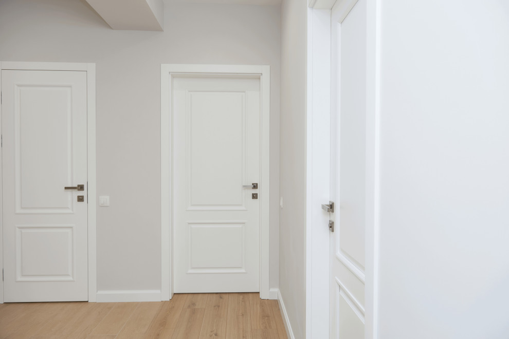 Пример оригинального дизайна: коридор среднего размера: освещение в современном стиле с белыми стенами, полом из ламината, коричневым полом и обоями на стенах