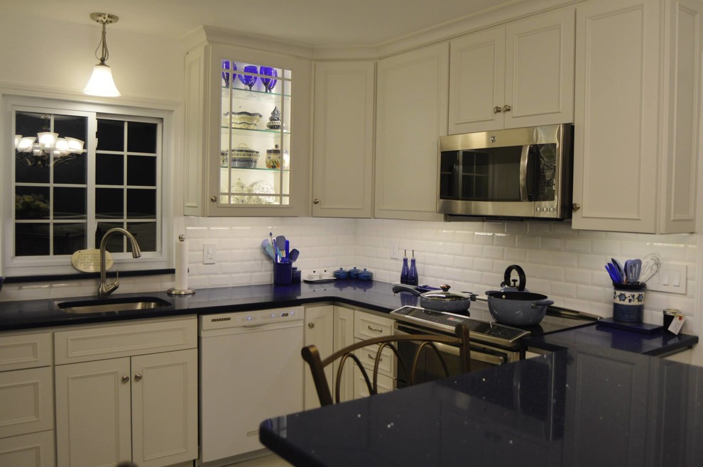 Large kitchen photo in Boston with white cabinets, white backsplash, stainless steel appliances and an island