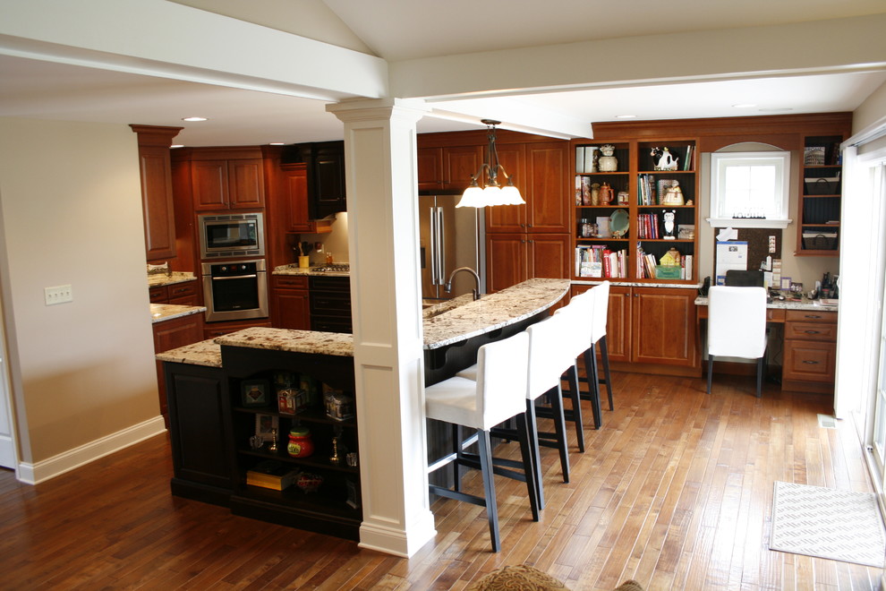 Photo of a mid-sized transitional u-shaped open plan kitchen in Philadelphia with raised-panel cabinets, dark wood cabinets, granite benchtops, beige splashback, stainless steel appliances, medium hardwood floors, multiple islands and a double-bowl sink.