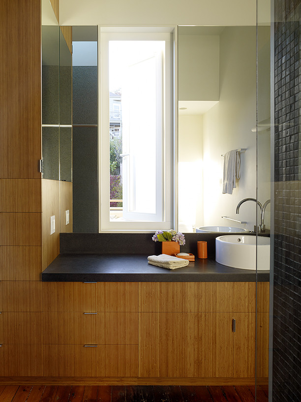 Photo of a modern bathroom in San Francisco with flat-panel cabinets, light hardwood floors, medium wood cabinets, grey walls and soapstone benchtops.
