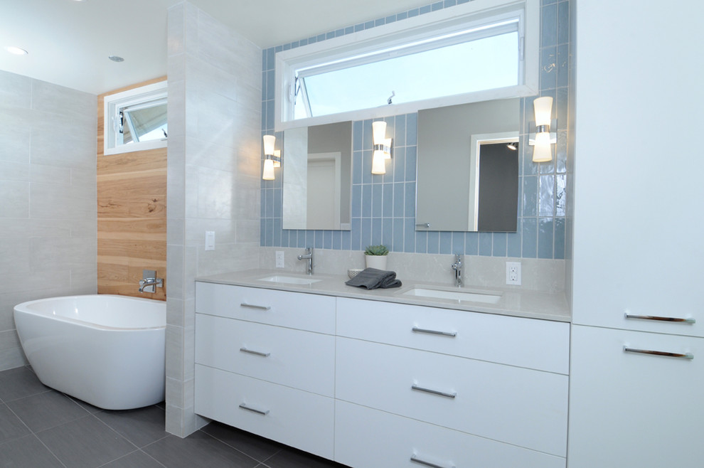 This is an example of a large midcentury bathroom in Los Angeles with flat-panel cabinets, white cabinets, a freestanding tub, an open shower, a one-piece toilet, porcelain tile, grey walls, porcelain floors, an undermount sink and laminate benchtops.