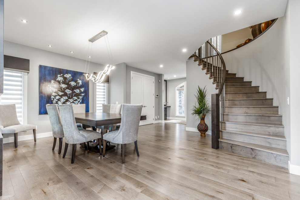 Large contemporary open plan dining room in Calgary with grey walls, medium hardwood flooring, a two-sided fireplace, a tiled fireplace surround and brown floors.