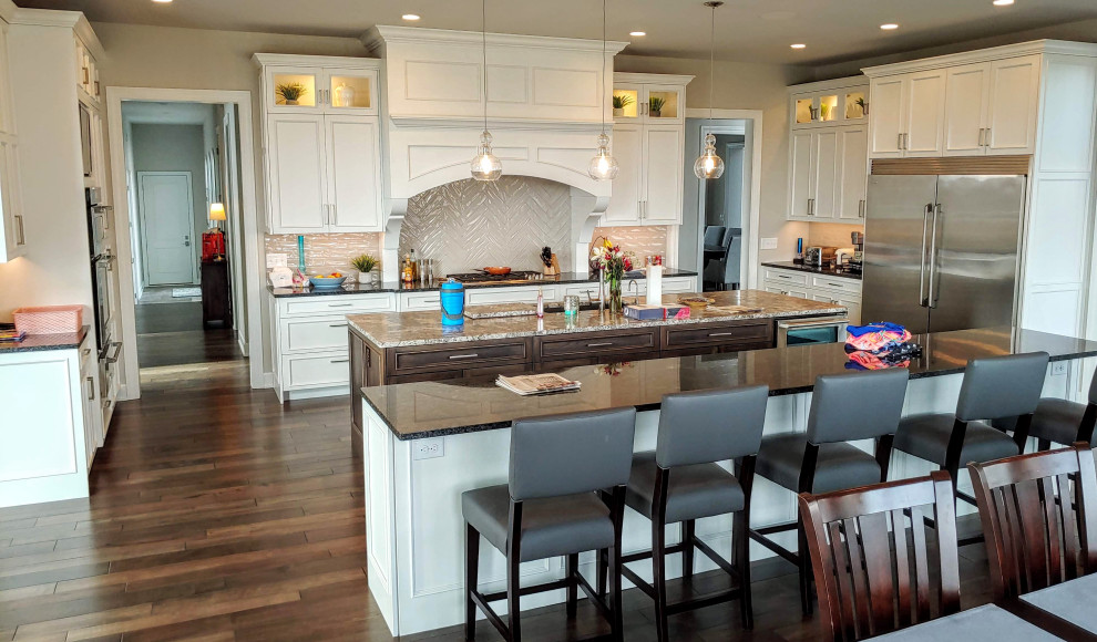 Eat-in kitchen - huge transitional dark wood floor and brown floor eat-in kitchen idea with recessed-panel cabinets, granite countertops, white backsplash, stainless steel appliances and two islands