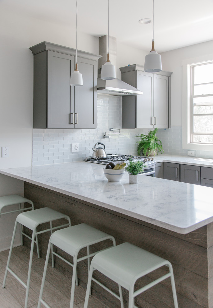 Inspiration for a mid-sized modern u-shaped open plan kitchen in Los Angeles with an undermount sink, shaker cabinets, grey cabinets, quartz benchtops, grey splashback, glass tile splashback, stainless steel appliances, light hardwood floors, a peninsula and multi-coloured benchtop.