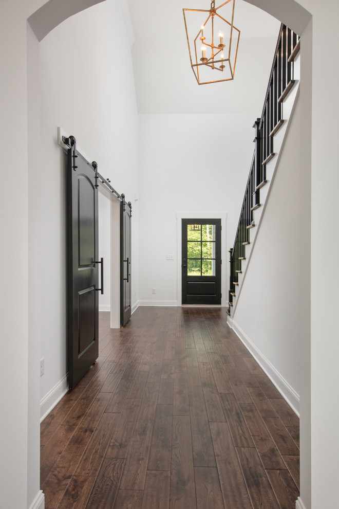 Photo of a large traditional foyer in Other with white walls, dark hardwood floors, a single front door, a black front door and brown floor.