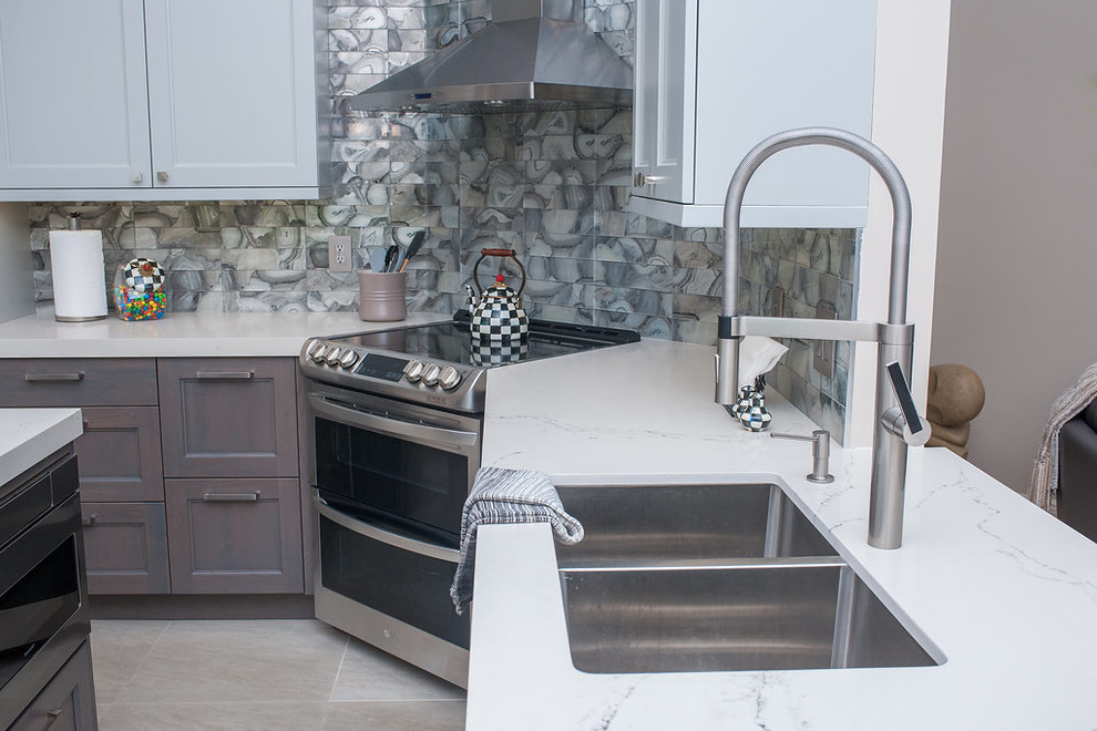 Example of a mid-sized transitional u-shaped porcelain tile and beige floor eat-in kitchen design in Miami with an undermount sink, shaker cabinets, gray cabinets, quartz countertops, gray backsplash, glass tile backsplash, stainless steel appliances, an island and white countertops