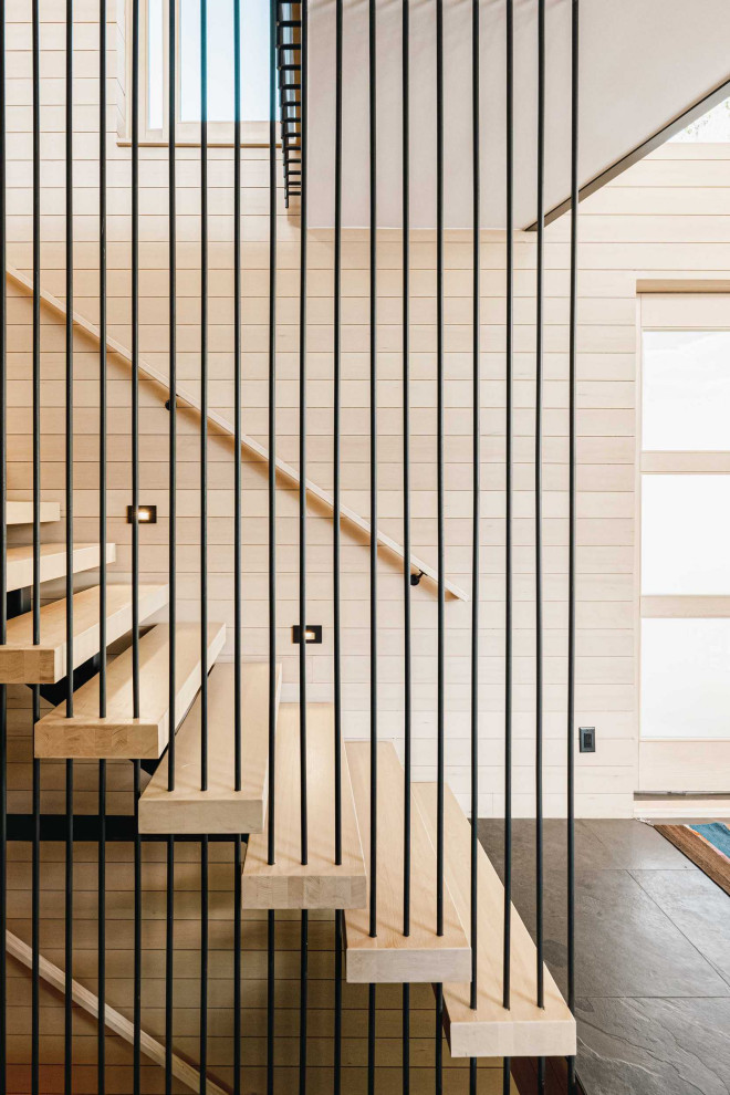 Imagen de escalera suspendida contemporánea sin contrahuella con escalones de madera, barandilla de metal y madera