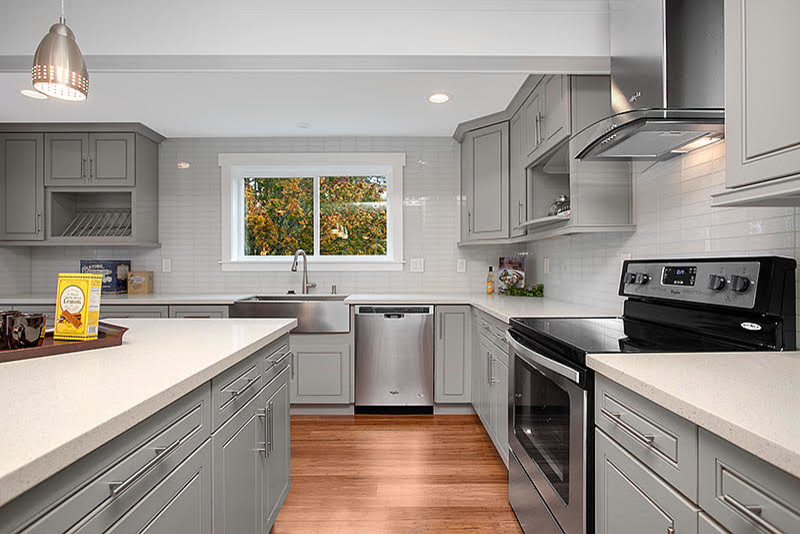 Eat-in kitchen - transitional medium tone wood floor eat-in kitchen idea in Seattle with raised-panel cabinets, gray cabinets, quartzite countertops, white backsplash, glass tile backsplash, stainless steel appliances and an island