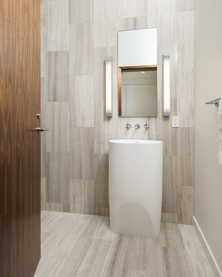 This is an example of a mid-sized modern powder room in Los Angeles with gray tile, stone tile, white walls, travertine floors and a pedestal sink.