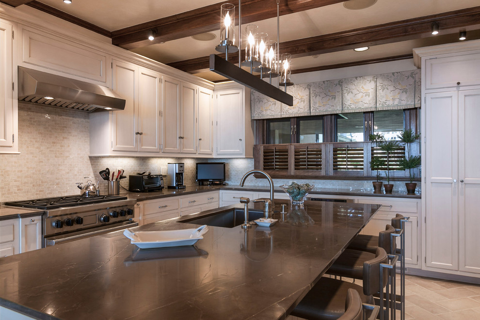 Transitional l-shaped separate kitchen in Santa Barbara with a single-bowl sink, raised-panel cabinets, beige cabinets, marble benchtops, beige splashback, ceramic splashback, stainless steel appliances, limestone floors and with island.
