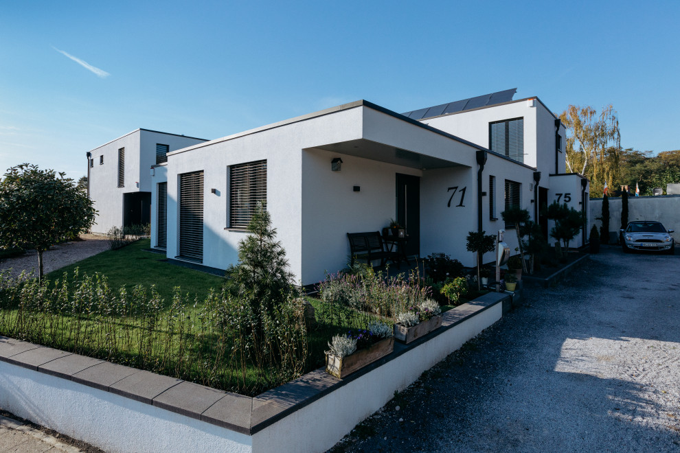 This is an example of an expansive contemporary two-storey stucco white exterior in Dusseldorf with a flat roof.
