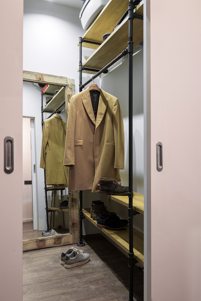 This is an example of a small industrial men's walk-in wardrobe in Moscow with laminate floors, open cabinets and brown floor.