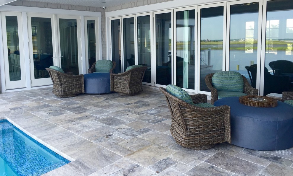 Photo of a mid-sized beach style backyard patio in Philadelphia with a water feature, natural stone pavers and a roof extension.