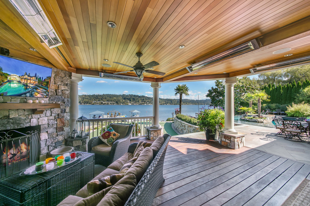 This is an example of an expansive traditional backyard and ground level deck in Seattle with with fireplace, a roof extension and wood railing.