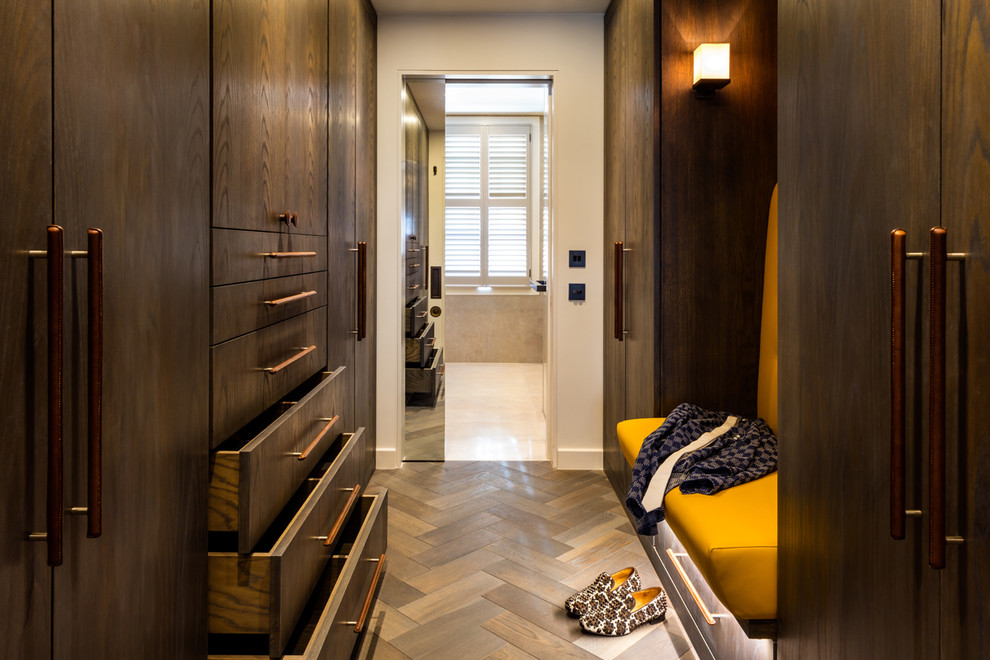 Inspiration for a mid-sized contemporary gender-neutral dressing room in London with flat-panel cabinets, dark wood cabinets and medium hardwood floors.