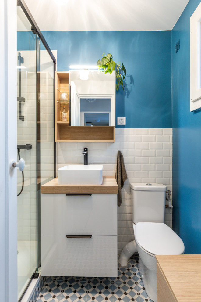 Photo of a small contemporary ensuite bathroom in Paris with beaded cabinets, light wood cabinets, a walk-in shower, a one-piece toilet, white tiles, metro tiles, blue walls, cement flooring, a console sink, wooden worktops, blue floors, a sliding door, beige worktops, a wall niche, a single sink and a floating vanity unit.