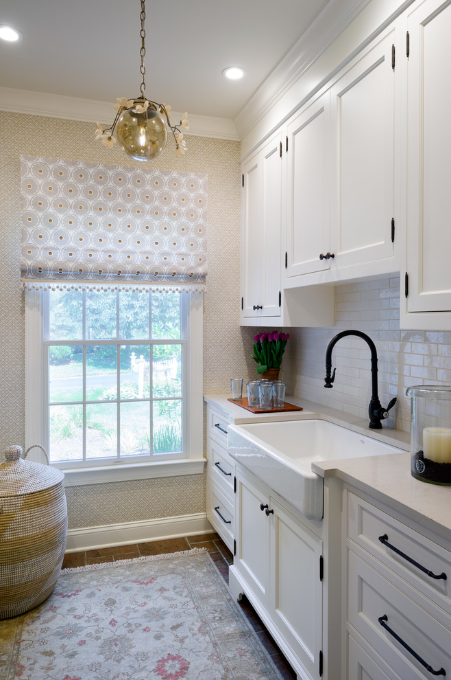 Inspiration for a small transitional laundry room in New York with a farmhouse sink, quartz benchtops, beige walls, porcelain floors, a side-by-side washer and dryer, beige benchtop, recessed-panel cabinets and white cabinets.