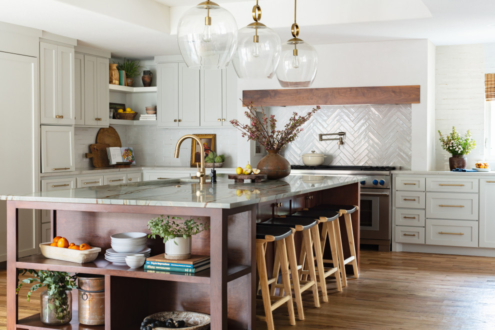 Klassisk inredning av ett mellanstort grön grönt kök och matrum, med luckor med infälld panel, beige skåp, bänkskiva i kvartsit, vitt stänkskydd, stänkskydd i keramik, rostfria vitvaror, ljust trägolv, en köksö och brunt golv