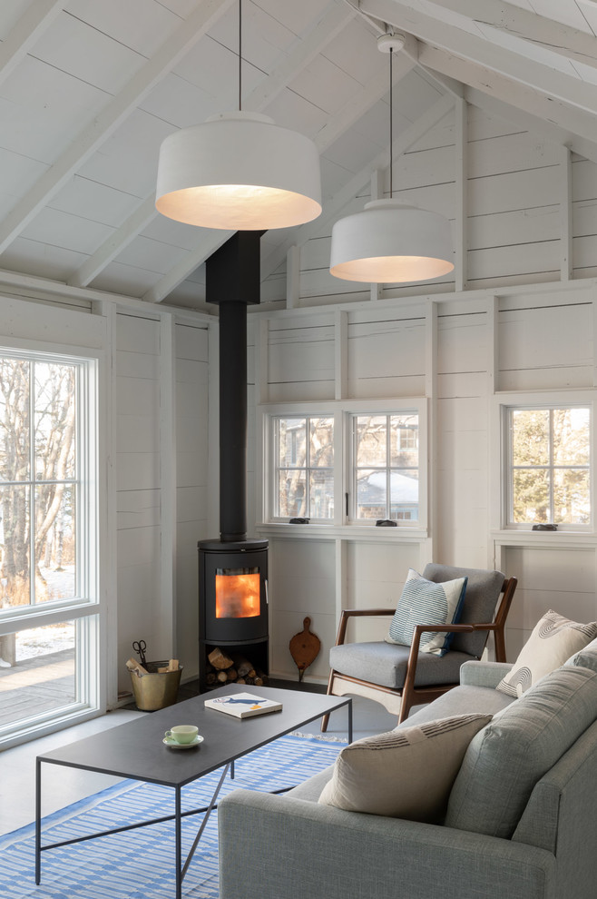 Beach style living room in Portland Maine with white walls, a wood stove and white floor.