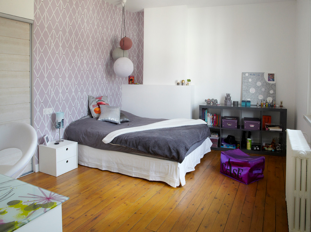 This is an example of a mid-sized country kids' room for girls in Lille with multi-coloured walls and light hardwood floors.