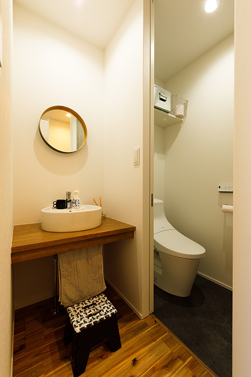 Mid-sized industrial powder room in Tokyo Suburbs with white tile, white walls, open cabinets, brown cabinets, a one-piece toilet, dark hardwood floors, a drop-in sink, wood benchtops, brown floor, brown benchtops, a built-in vanity, wallpaper and wallpaper.