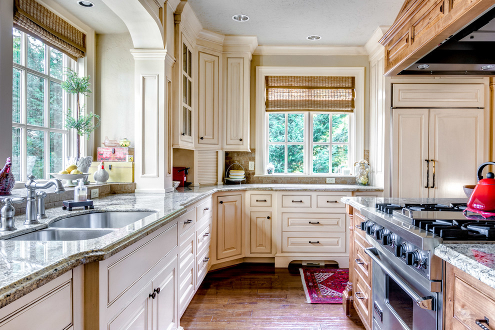 Design ideas for a traditional u-shaped kitchen in Portland with a double-bowl sink, raised-panel cabinets, beige cabinets, panelled appliances, medium hardwood floors and with island.