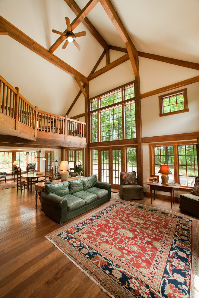 Photo of a large traditional loft-style living room in Manchester with white walls, medium hardwood floors, a standard fireplace and a stone fireplace surround.